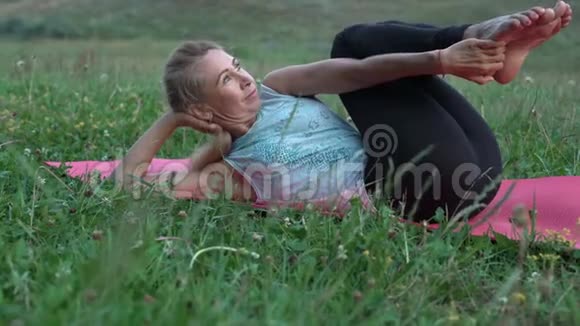 美丽的女人表演瑜伽藤本植物躺在地毯上视频的预览图