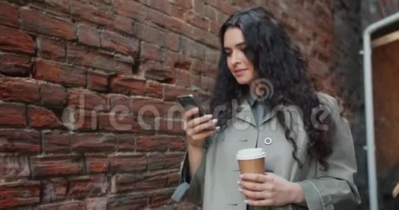 快乐的女人用智能手机触摸屏幕微笑着走在户外视频的预览图