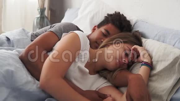 多种族夫妇躺在床上睡觉相互拥抱的特写镜头年轻家庭观念视频的预览图