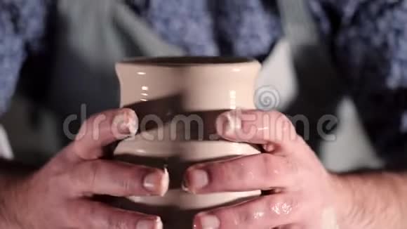 在车轮上旋转的半成品陶瓷花瓶的镜头关闭在陶工跳汰机上工作的男性手小型企业视频的预览图