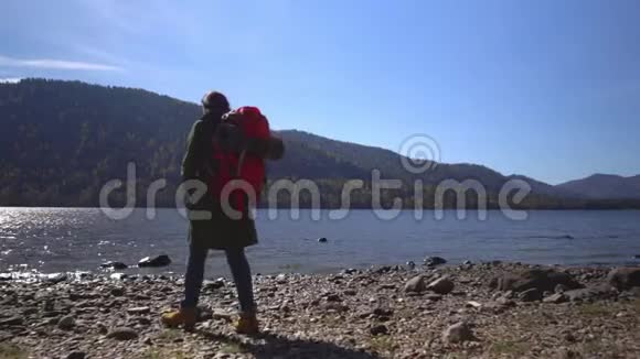 山湖堕落那个带着红色背包的旅行者的女人在湖岸上花钱视频的预览图