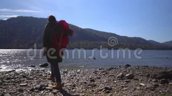 山湖堕落那个带着红色背包的旅行者的女人在湖岸上花钱视频的预览图