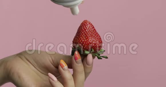 女人的手拿着草莓在浆果上面挤出鲜奶油视频的预览图