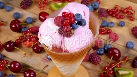 杯中的水果冰淇淋在满是森林水果的桌子上旋转视频的预览图