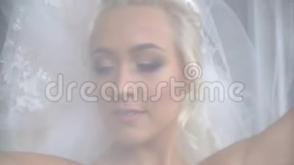 美丽美丽的金发新娘的肖像迷人的微笑在面纱下摆着视频的预览图