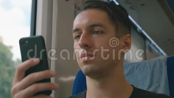 年轻人在火车上使用智能手机录音和滚动视频的预览图