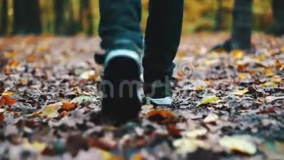 秋天公园里一个黄叶男孩的脚特写一个男孩穿过森林里黄色的落叶视频的预览图