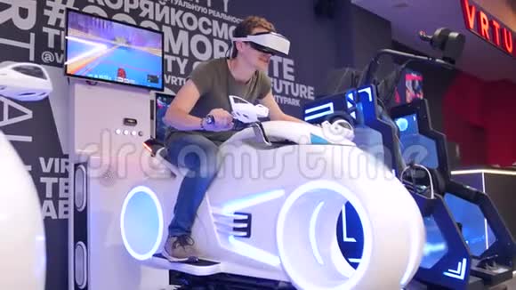 年轻迷人的帅哥在虚拟现实中骑摩托车假期创新屏幕霓虹灯自行车酷视频的预览图