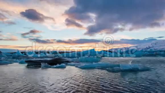 日落时分漂浮在约库萨尔隆冰川泻湖的蓝色冰山的时间流逝视频的预览图