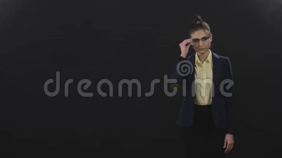 穿商务套装的有影响力的专家女孩站在工作室的黑色背景上视频的预览图