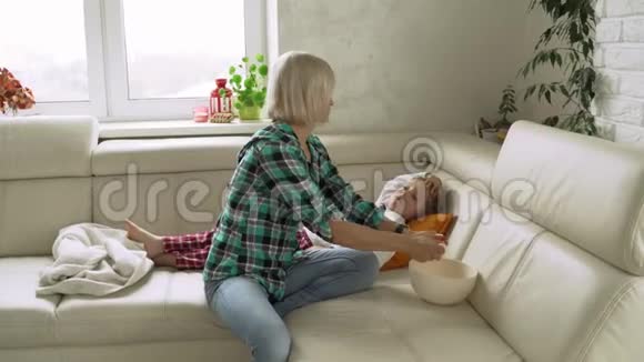 小男孩坐在沙发上头上戴着较冷的凝胶用温度计测量温度并照顾她视频的预览图