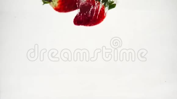 草莓掉进水里有很多小气泡孤立的白色背景上的水果视频的预览图