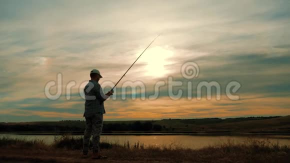 在美丽的日落中享受钓鱼的人剪影视频的预览图