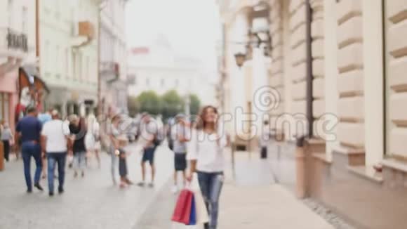 街上拿着购物袋的年轻女子用手机说话视频的预览图