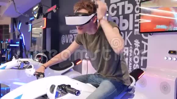 年轻迷人的帅哥在虚拟现实中骑摩托车假期创新屏幕霓虹灯自行车酷视频的预览图