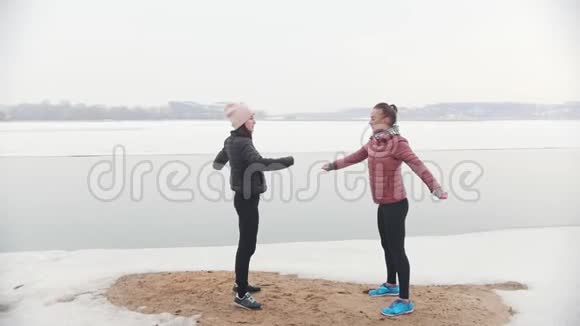 两个苗条的女人站在雪地上为跑步热身视频的预览图