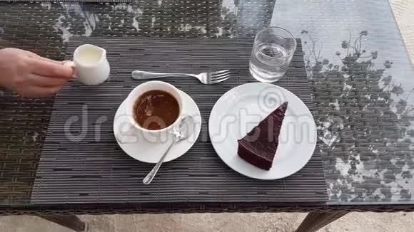 桌上有咖啡蛋糕和水雌性手倒在牛奶里食饮概念美丽的背景视频的预览图
