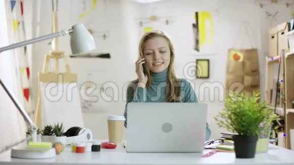 年轻女子用笔记本电脑谈论智能手机视频的预览图