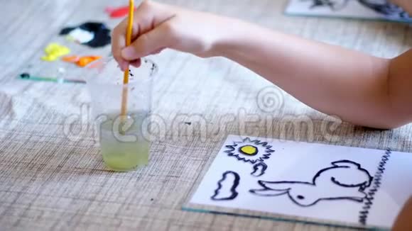 绘画教室特写孩子们手在玻璃里洗一把画笔画画女孩用颜色画画主人视频的预览图