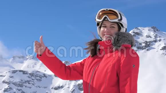 一个年轻漂亮的女人微笑着给一个拇指在雪山背景视频的预览图