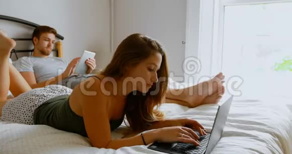 使用笔记本电脑和数码平板电脑的情侣床4k视频的预览图