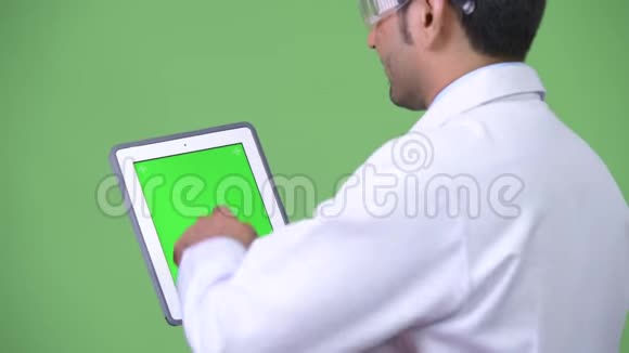 年轻帅气的波斯男医生戴着护目镜展示数码平板电脑视频的预览图