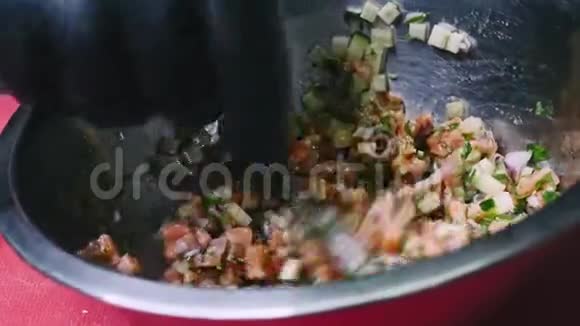 番茄黄瓜和欧芹色拉用勺子在金属碗中搅拌在黑色手套中缓慢移动分辨率为4k视频的预览图