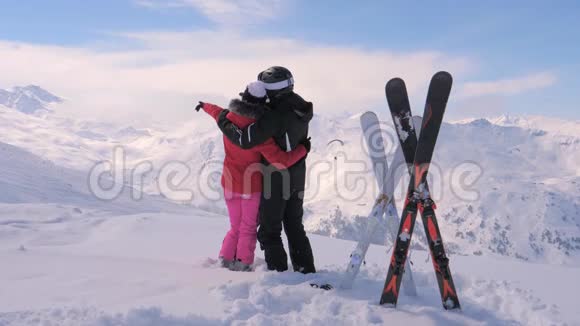 恋爱中的情侣站在雪山的顶端双手移动视频的预览图