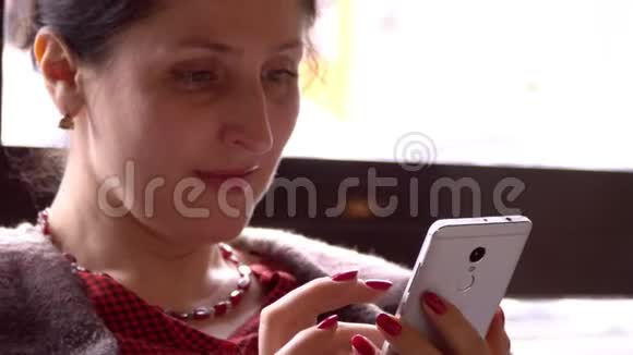 女人在智能手机上使用应用程序在咖啡馆里喝咖啡微笑着在手机上发短信美丽的多元文化青年视频的预览图