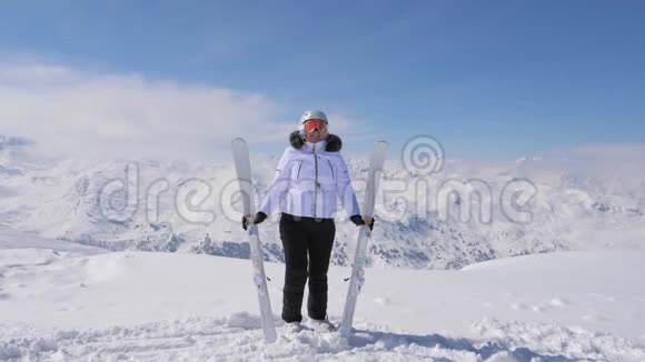 快乐的女人在山顶上举起她的下坡滑雪板视频的预览图