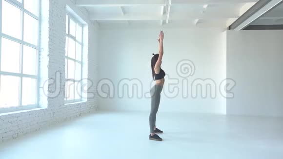 侧面完整的观看运动女运动员做蹲和举手工作室的位置视频的预览图