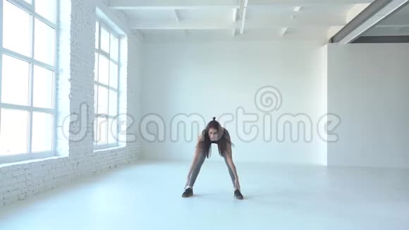 年轻的健身女子正在做蹲和举手热身运动工作室的位置视频的预览图