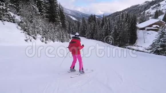 女滑雪者沿着滑雪路线下山在松林中的山坡上视频的预览图