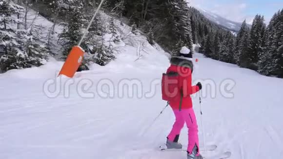 女滑雪者沿着滑雪路线下山在松林中的山坡上视频的预览图