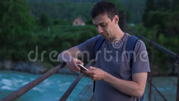 一个孤独的游客拿着手机站在桥上视频的预览图