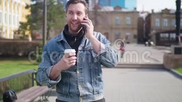 一个穿着休闲服的男人走在街上在咖啡休息时打电话视频的预览图