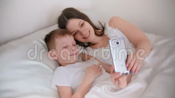妈妈和儿子在手机上自拍妈妈拥抱她的儿子视频的预览图