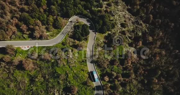 蓝色公共汽车在山路鸟瞰图上左转危险的狭窄森林车道交通道路安全旅行4K视频的预览图