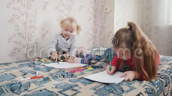 两个小女孩躺在床上画画视频的预览图