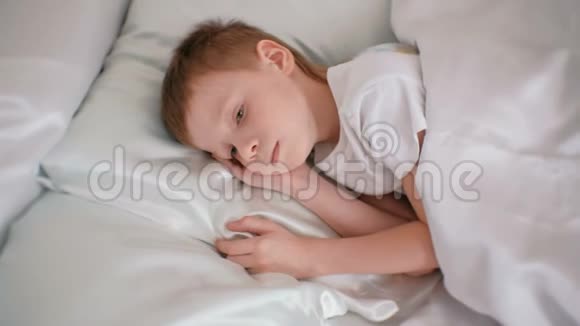 七岁的男孩静静地躺在他的房间里的床上把手放在他的头下视频的预览图
