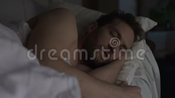睡在床上的成年长胡子男人白天累人睡眠良好晚上休息视频的预览图