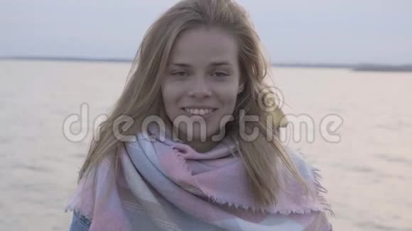 美丽的幸福女人站在海边夕阳下的肖像视频的预览图