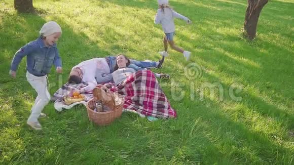 父母躺在草地上他们的两个女儿在公园里玩得很开心也有跑步的背景家庭度假景观视频的预览图