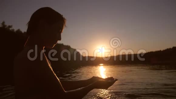 美丽的女孩被戏水站在河边对着夕阳在天空中微笑视频的预览图