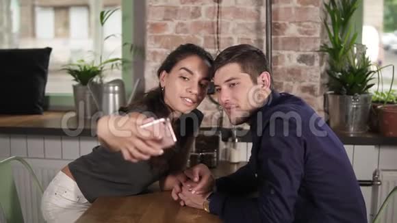 漂亮的年轻夫妇在餐馆咖啡馆自拍节日快乐的一对情侣坐着自拍视频的预览图