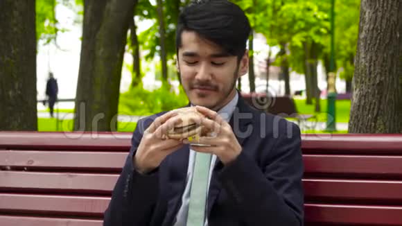 商人在公园里吃美味的汉堡视频的预览图
