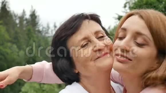 户外特写照片微笑的快乐的白种人高级母亲与她的成年女儿拥抱和看着她的成年女儿视频的预览图