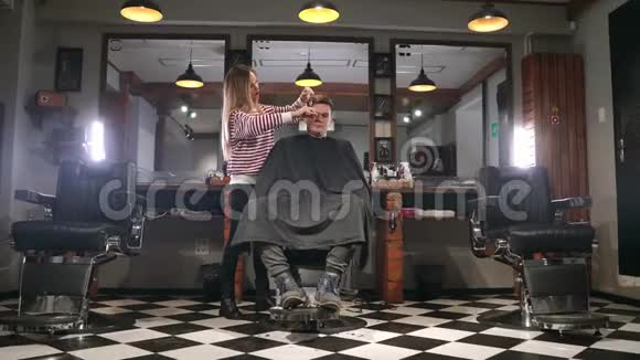 男子客户参观理发店的理发师和发型师的后视图视频的预览图