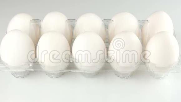 白色背景的透明塑料托盘中的大白鸡蛋女性手从托盘里拿鸡蛋视频的预览图