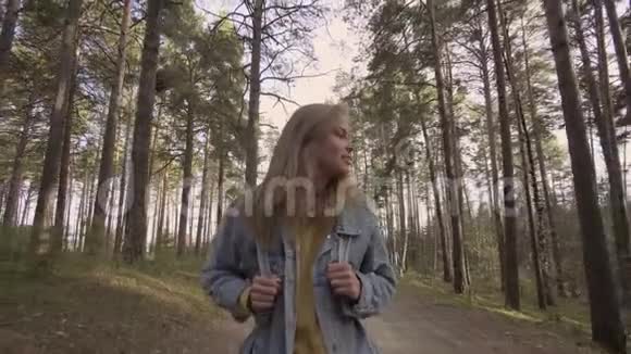 年轻的微笑女孩走在秋天的森林里视频的预览图